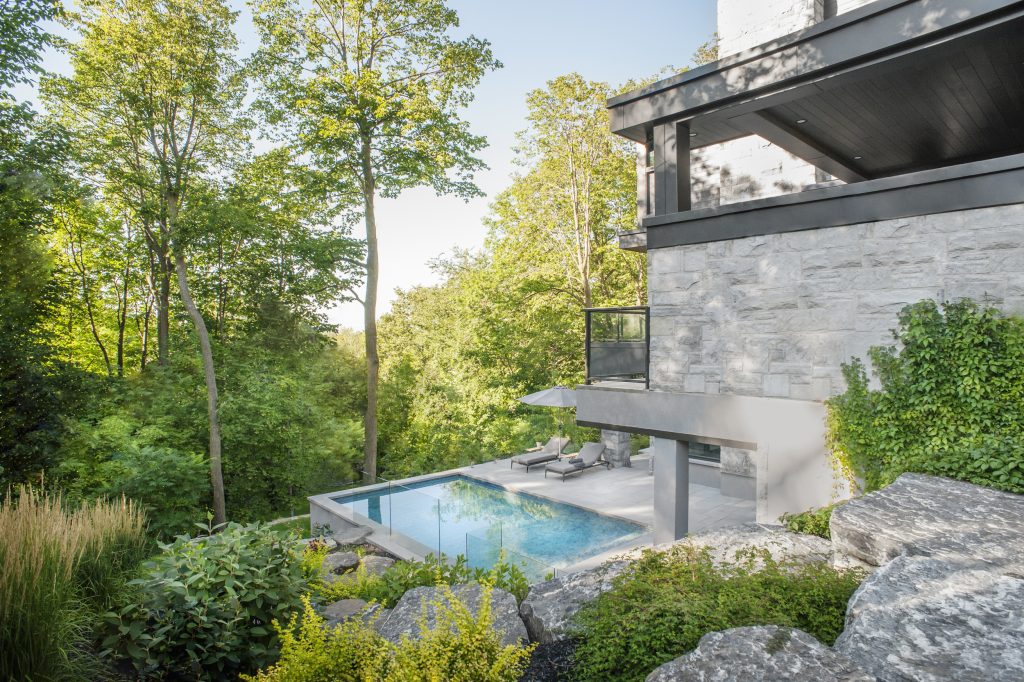 Aménagement paysager sur terrain très en pente avec maison contemporaine intégrée dans un environnement boisé avec matériaux nobles et durables